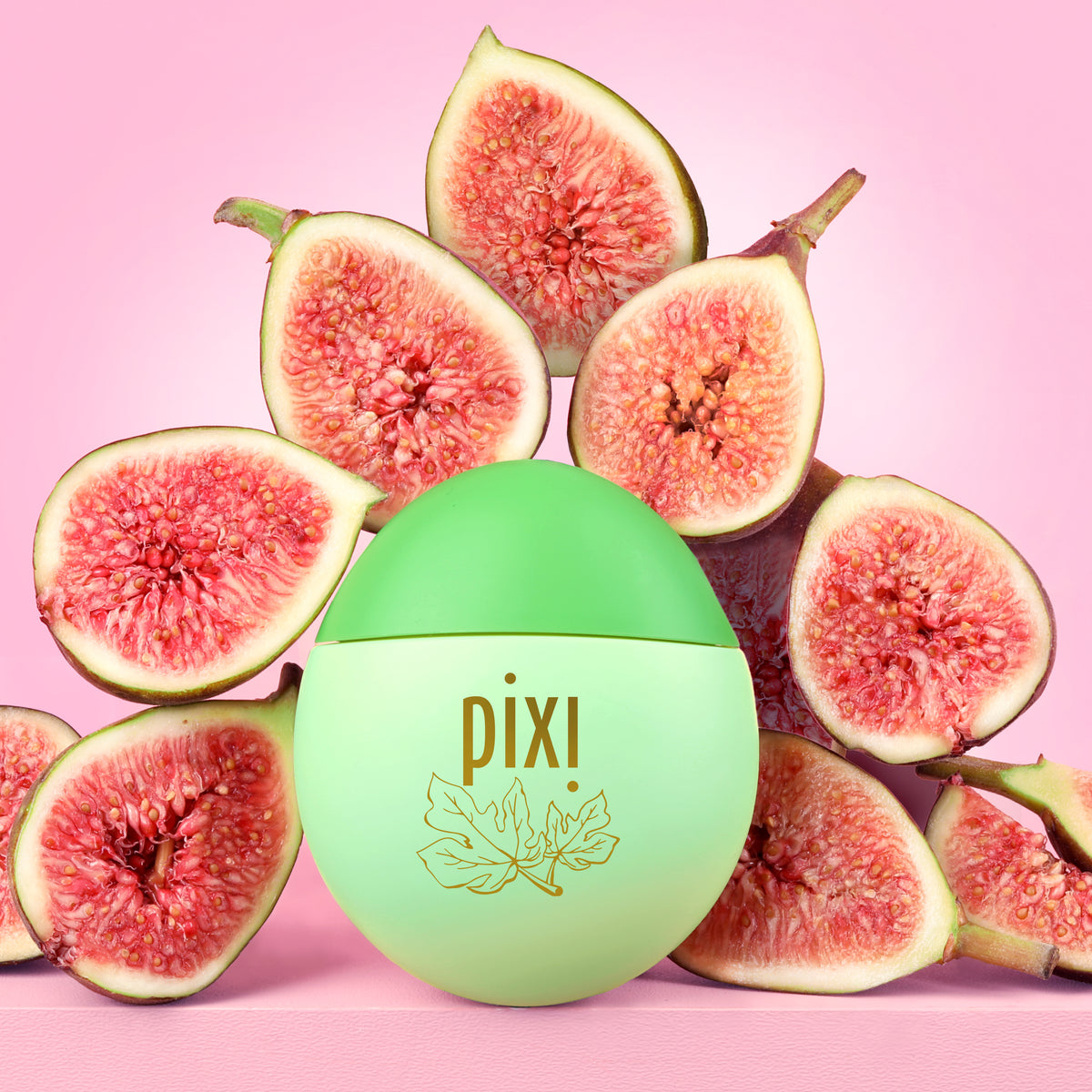 Pixi HandHero hand lotion surrounded by fresh sliced figs, a light green gradient with gold leaf logo on a pink background.
